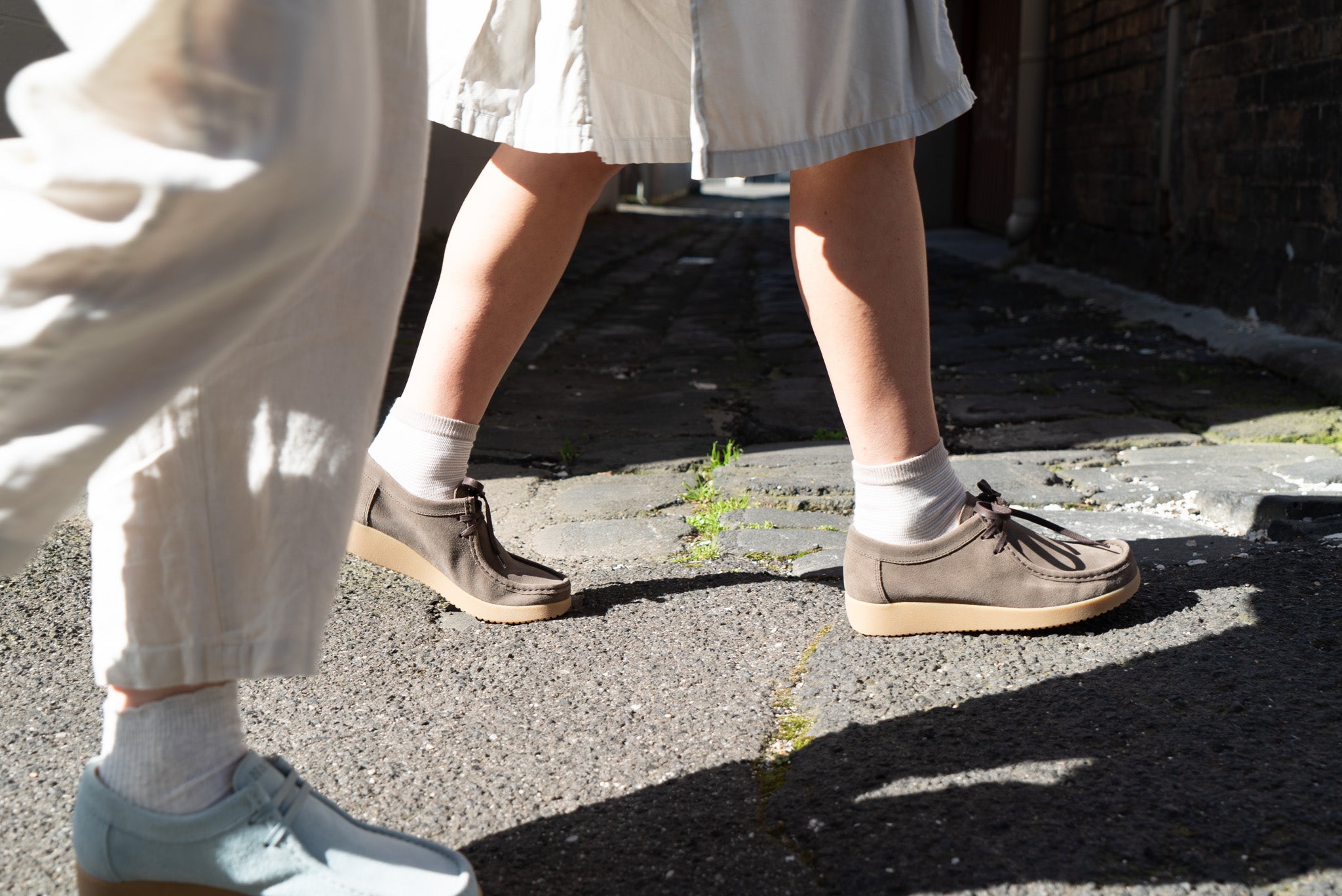 Two women walking on a city path, wearing Clay and Sky coloured shoes.